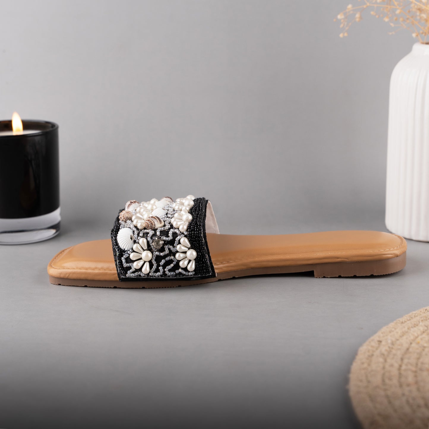 Coastal-inspired black slip-on sliders with a textured strap resembling sea shells