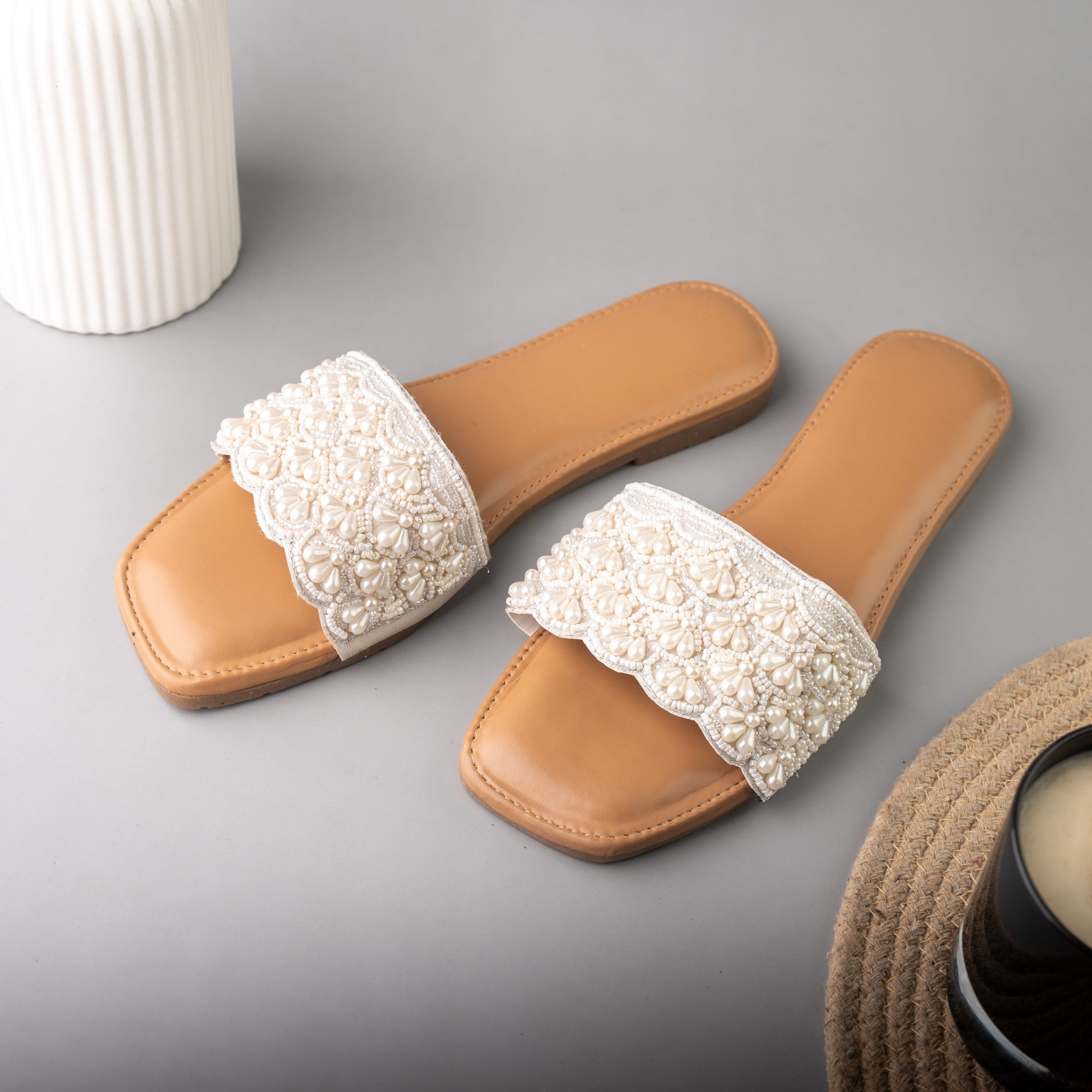 Lightweight beige summer slides featuring an intricately designed lace-style white strap